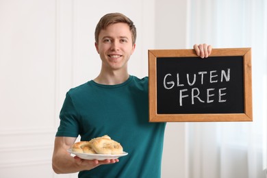 Photo of Man holding small chalkboard with text Gluten Free and pretzels indoors