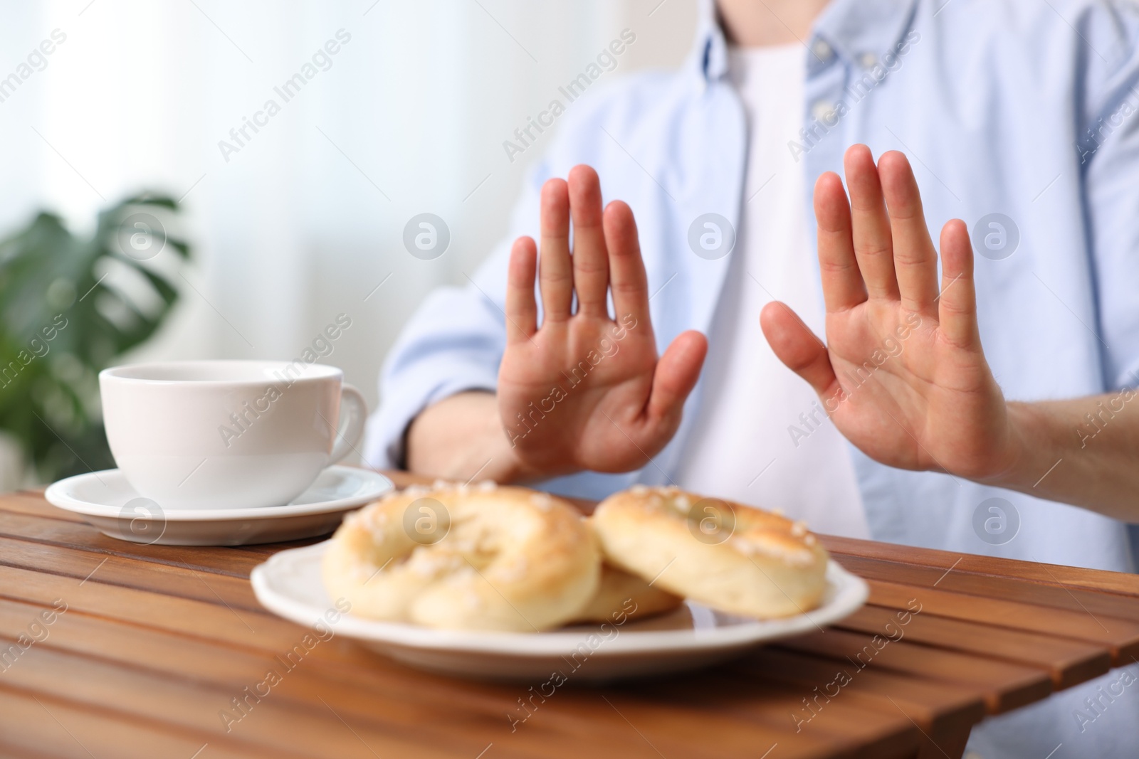 Gluten free diet. Man refusing from pastries at wooden table indoors, closeup Photo of Gluten free diet. Man refusing from pastries at wooden table indoors, closeup
