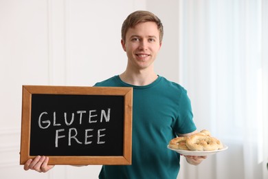 Photo of Man holding small chalkboard with text Gluten Free and pretzels indoors