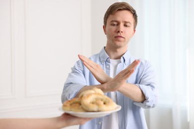 Photo of Gluten free diet. Man refusing from pastries indoors, selective focus