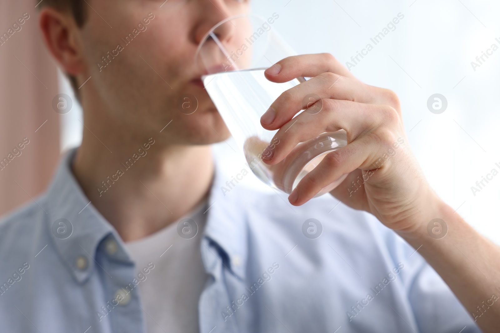 Man drinking water from glass at home, closeup Photo of Man drinking water from glass at home, closeup