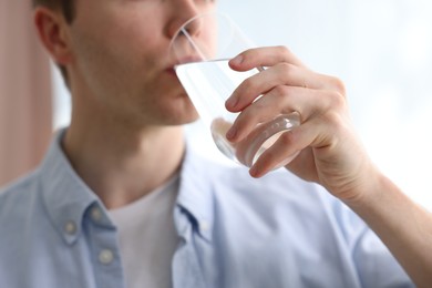 Photo of Man drinking water from glass at home, closeup