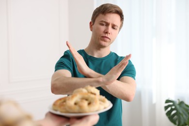 Photo of Gluten free diet. Man refusing from pastries indoors, selective focus