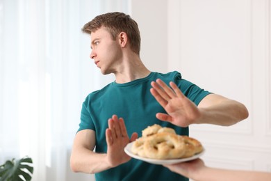 Photo of Gluten free diet. Man refusing from pastries indoors, selective focus