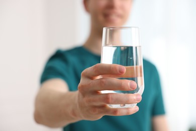 Photo of Man with glass of water at home, selective focus