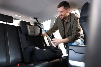 Photo of Happy man with child safety seat inside car