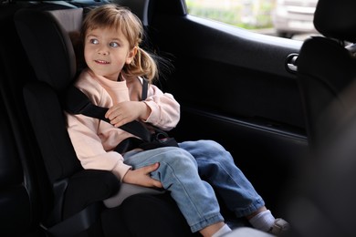 Photo of Little girl sitting in child safety seat inside car