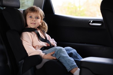 Photo of Little girl sitting in child safety seat inside car