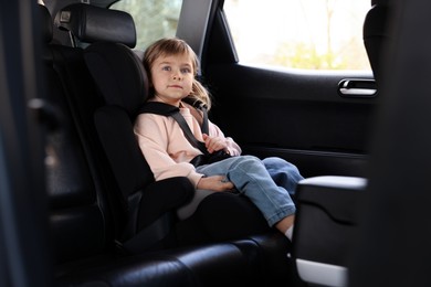 Photo of Little girl sitting in child safety seat inside car