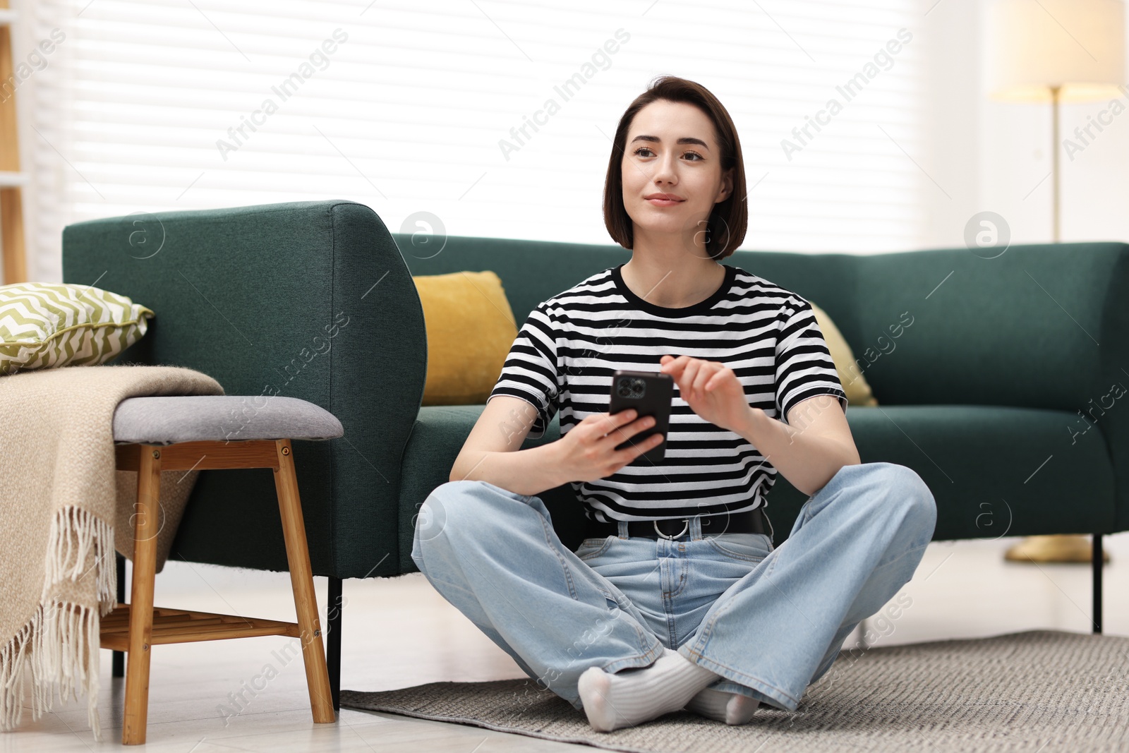 Woman using modern smartphone on floor at home Photo of Woman using modern smartphone on floor at home