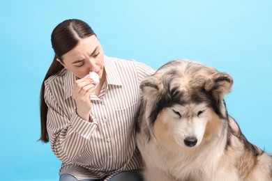 Photo of Woman suffering from allergy with her dog on light blue background