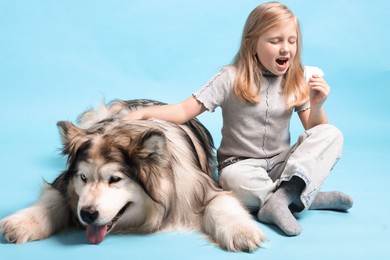 Photo of Girl suffering from allergy with her dog on light blue background