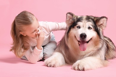 Photo of Girl suffering from allergy with her dog on pink background