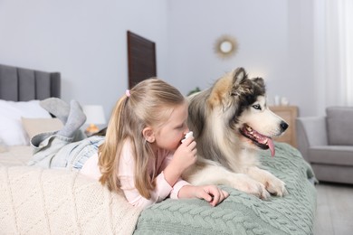 Photo of Girl suffering from allergy with her dog on bed at home