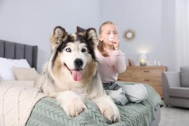 Photo of Girl suffering from allergy with her dog on bed at home