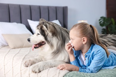 Photo of Girl suffering from allergy with her dog on bed at home