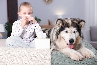 Photo of Girl suffering from allergy with her dog on bed at home