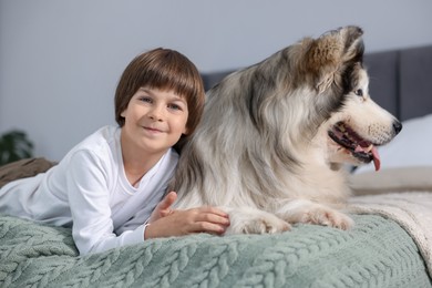 Photo of Happy boy and cute dog on bed at home