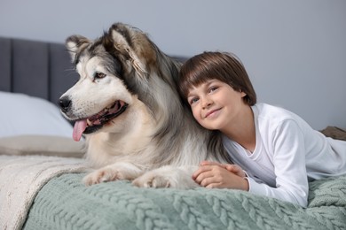 Photo of Happy boy and cute dog on bed at home