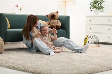 Photo of Happy mother spending time together with her son on floor at home