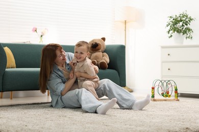 Photo of Happy mother spending time together with her son on floor at home