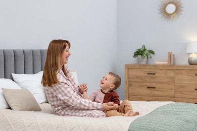 Photo of Happy mother spending time together with her son on bed at home