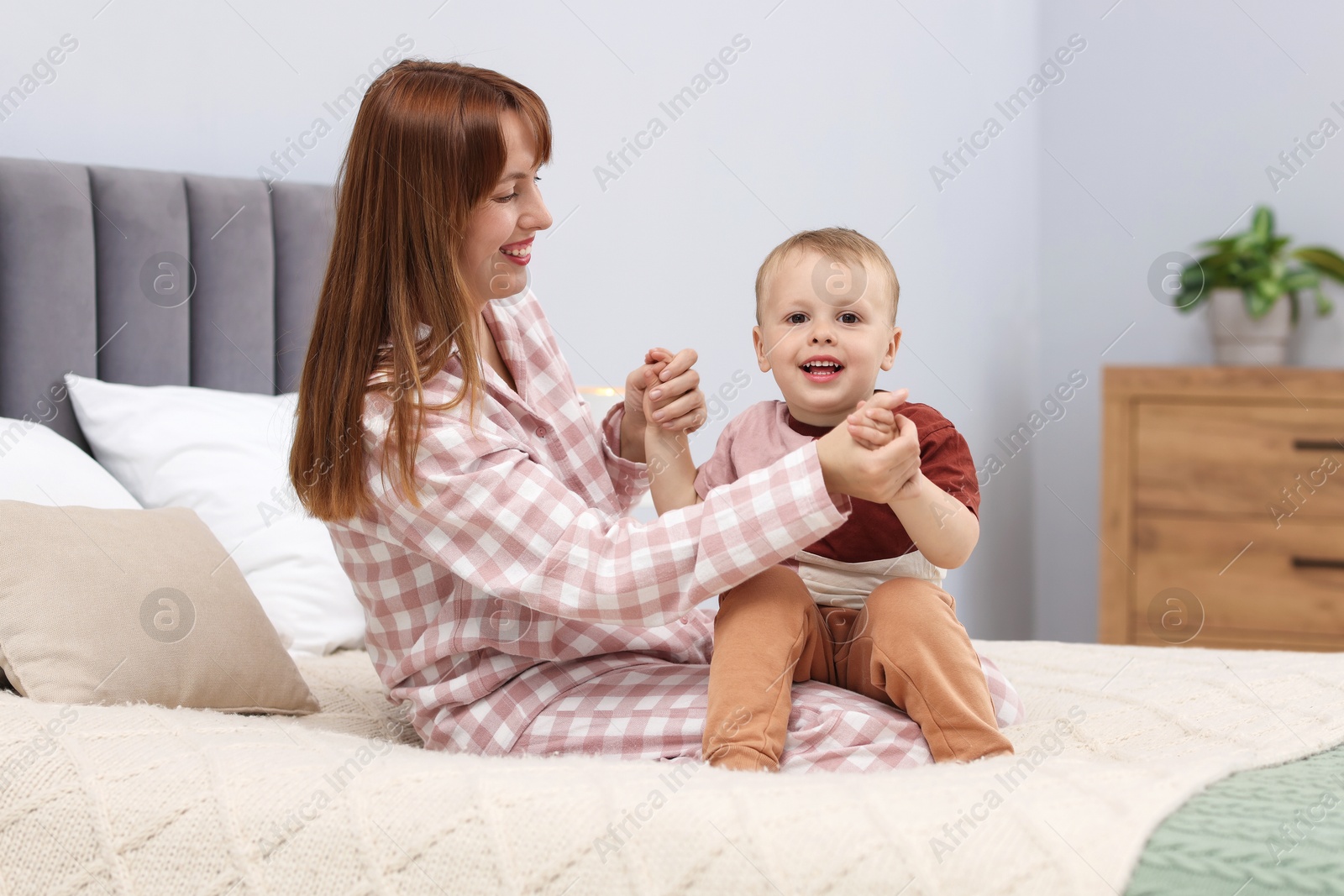 Happy mother spending time together with her son on bed at home Photo of Happy mother spending time together with her son on bed at home