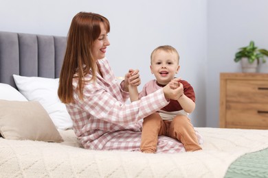 Photo of Happy mother spending time together with her son on bed at home