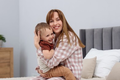 Photo of Happy mother hugging her son on bed at home