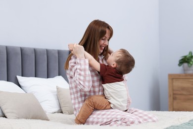 Photo of Happy mother playing with her son on bed at home