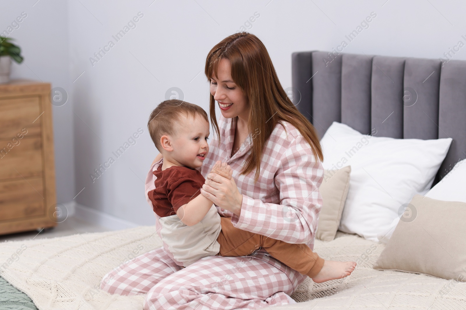 Happy mother playing with her son on bed at home Photo of Happy mother playing with her son on bed at home