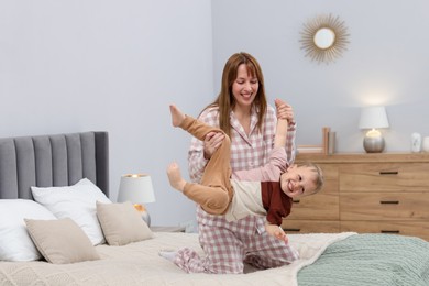 Photo of Happy mother playing with her son on bed at home