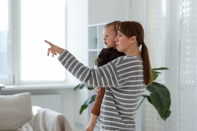 Photo of Mother showing something to her son at home