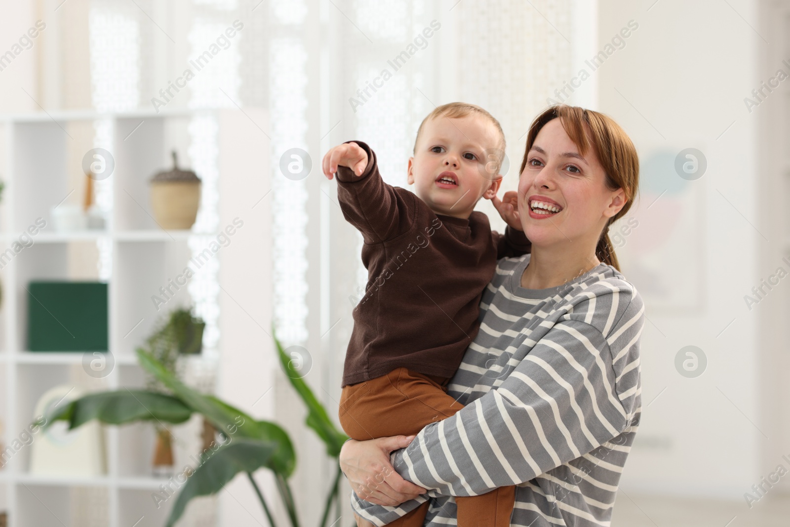 Little son showing something to his happy mother at home. Space for text Photo of Little son showing something to his happy mother at home. Space for text
