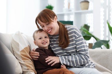 Photo of Happy mother spending time together with her son on sofa at home