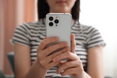 Photo of Woman using modern smartphone at home, closeup