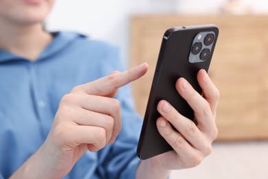 Photo of Woman using modern smartphone at home, closeup