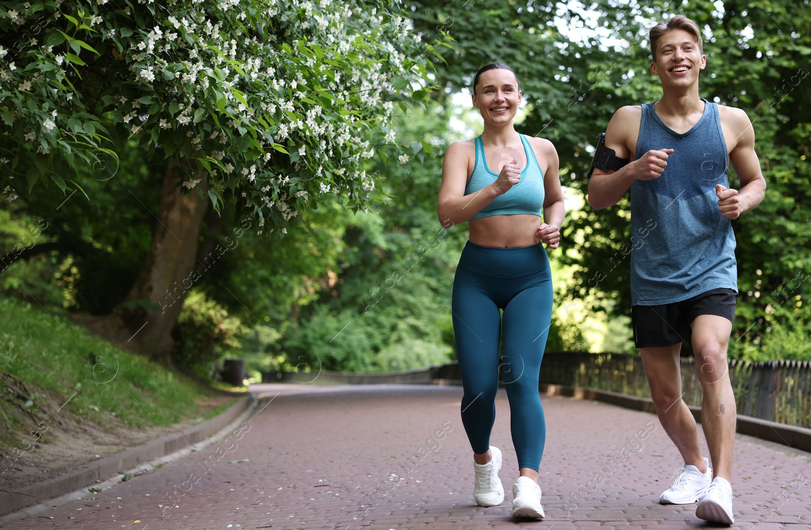 Sporty couple running in park, space for text. Healthy lifestyle Photo of Sporty couple running in park, space for text. Healthy lifestyle