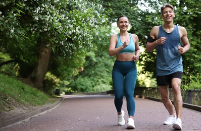 Photo of Sporty couple running in park, space for text. Healthy lifestyle