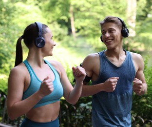 Photo of Sporty couple with headphones running in park
