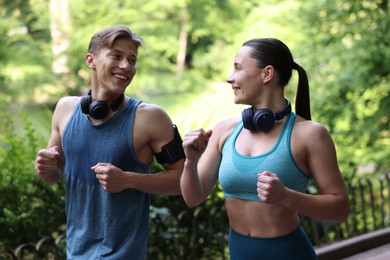 Photo of Sporty couple with headphones running in park
