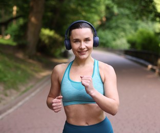 Photo of Sporty woman with headphones running in park