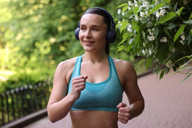 Photo of Sporty woman with headphones running in park