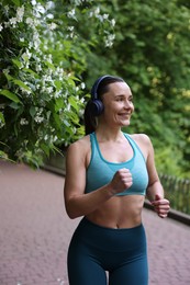 Photo of Sporty woman with headphones running in park