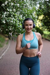 Photo of Sporty woman with headphones running in park