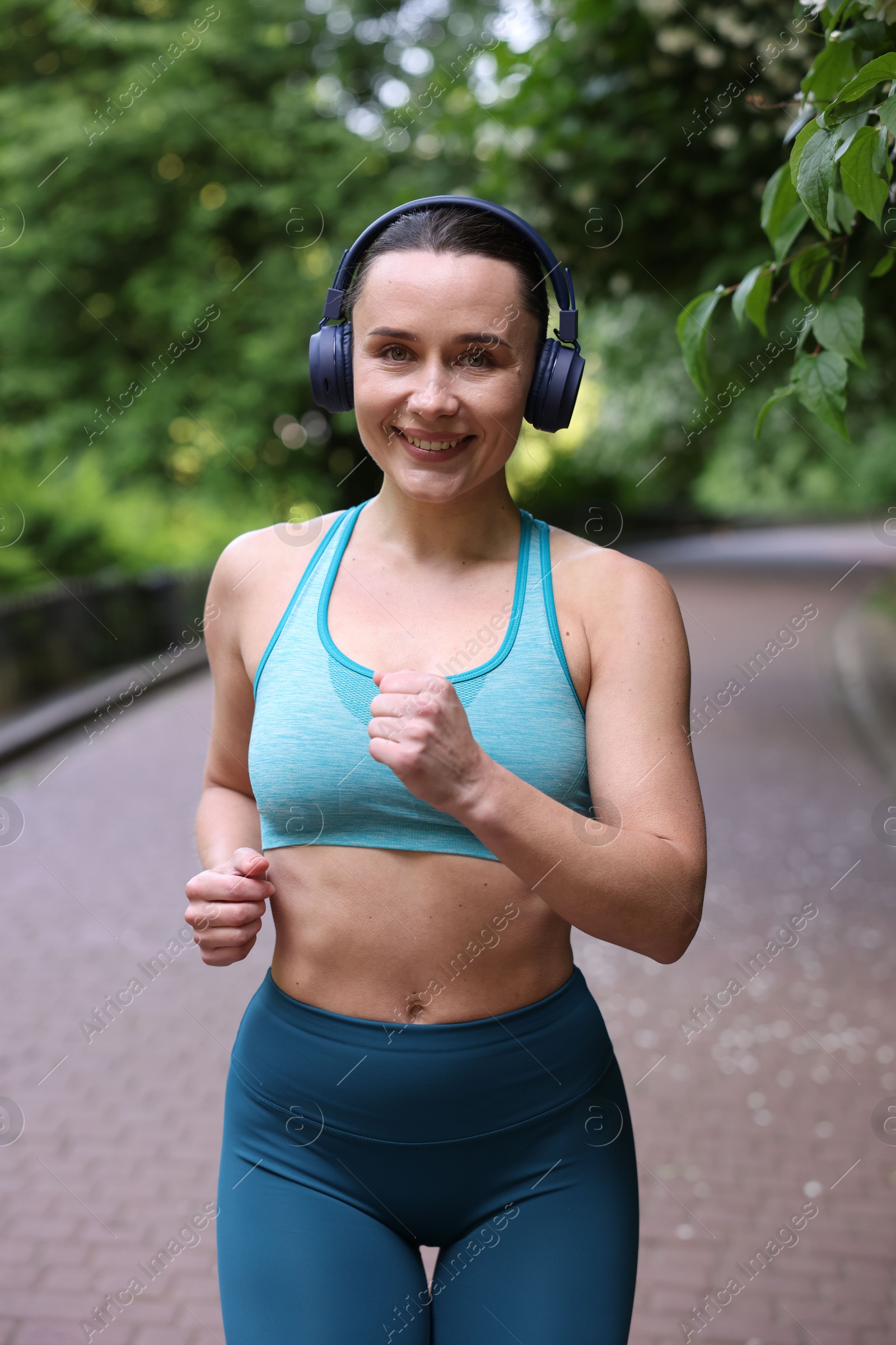 Sporty woman with headphones running in park Photo of Sporty woman with headphones running in park
