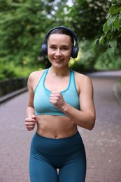 Photo of Sporty woman with headphones running in park