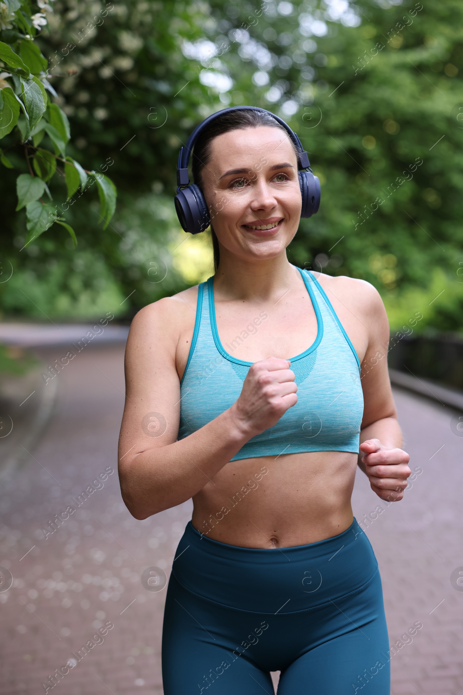 Sporty woman with headphones running in park Photo of Sporty woman with headphones running in park