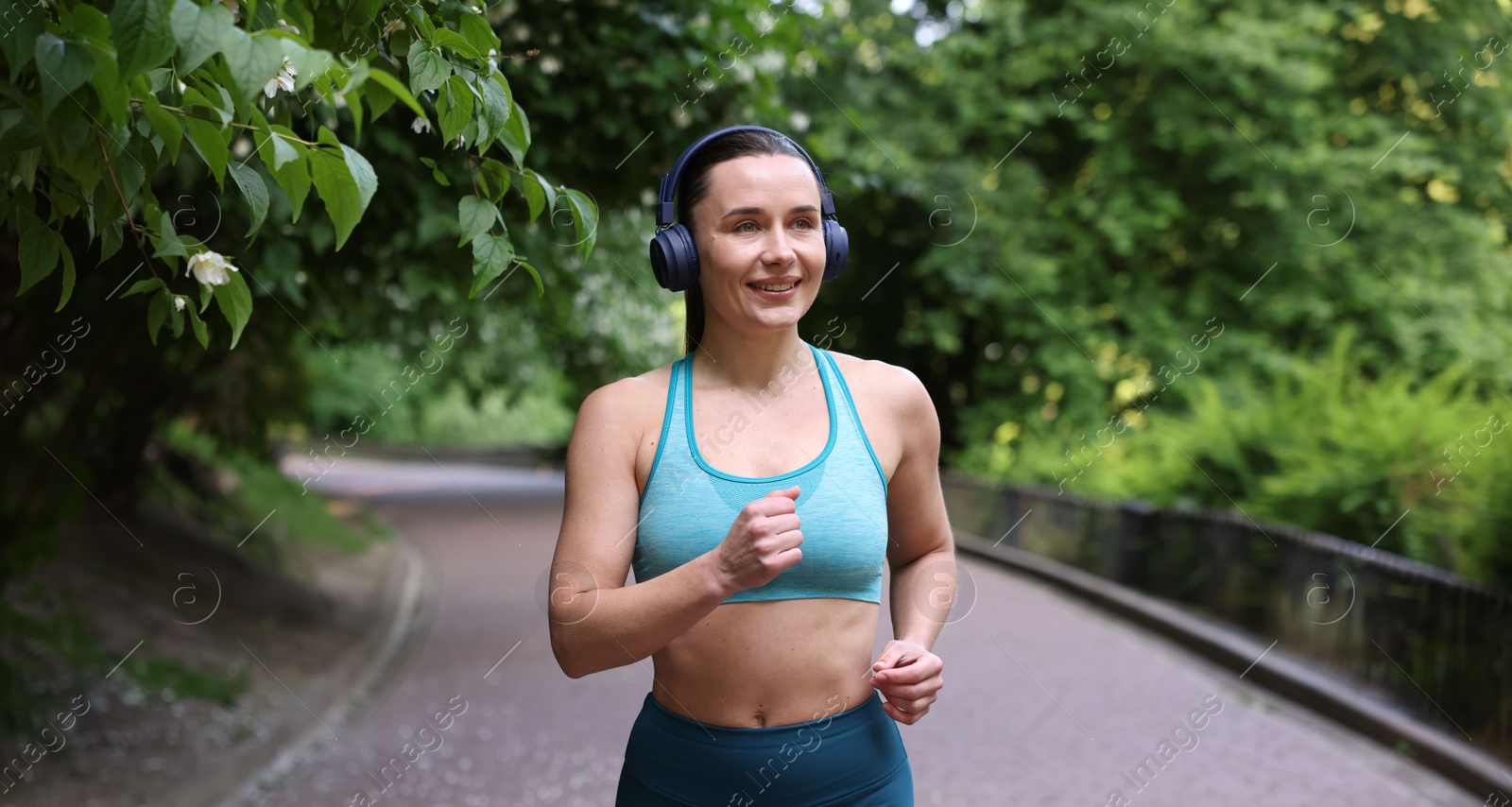 Sporty woman with headphones running in park Photo of Sporty woman with headphones running in park