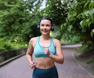 Photo of Sporty woman with headphones running in park